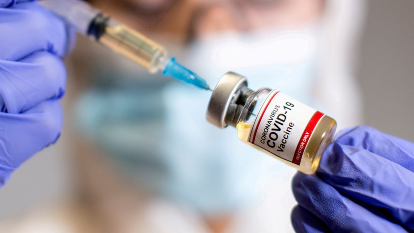 FILE PHOTO: A woman holds a medical syringe and a small bottle labeled "Coronavirus COVID-19 Vaccine