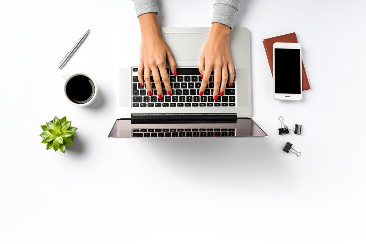 praca, komputer, ręce, dłonie, telefon, kawa, spinacz, długopis, roślina, biurko, laptop. / fot. Shutterstock