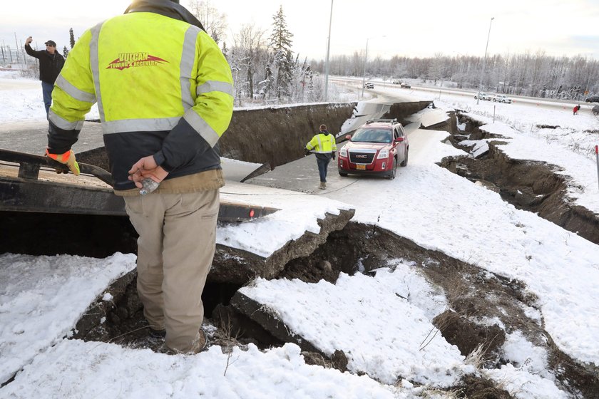 A vehicle lies stranded on a collapsed roadway near the airport after an earthquake in Anchorage