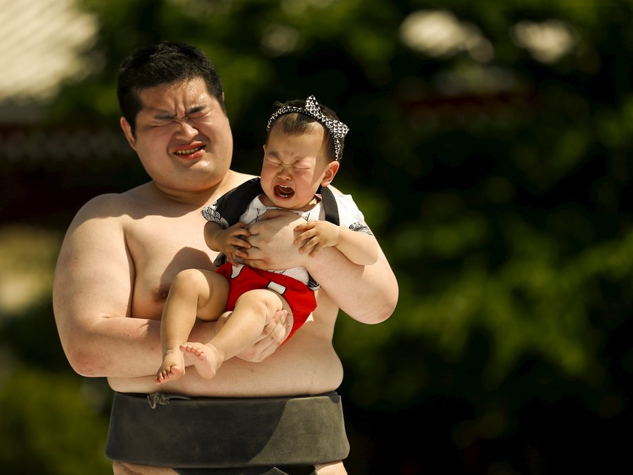 An amateur sumo wrestler holds a baby during a baby crying contest at Sensoji temple in Tokyo May 30, 2015.