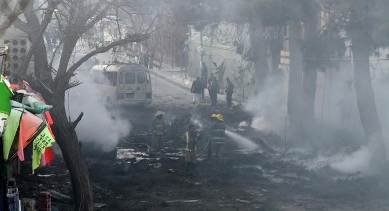 Firefighters work to extinguish a fire at the site of an explosion which struck a bus during rush hour in downtown Kabul on March 13, 2017