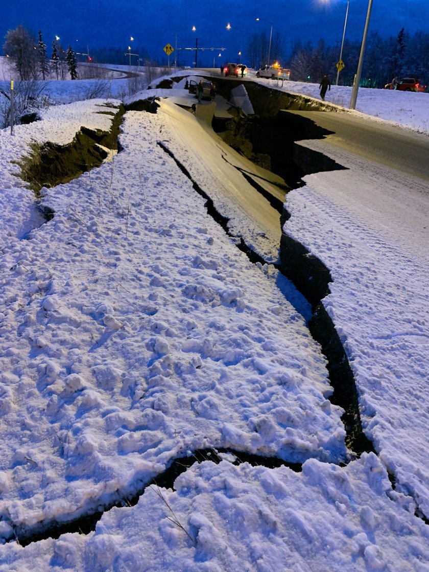 A vehicle lies stranded on a collapsed roadway near the airport after an earthquake in Anchorage