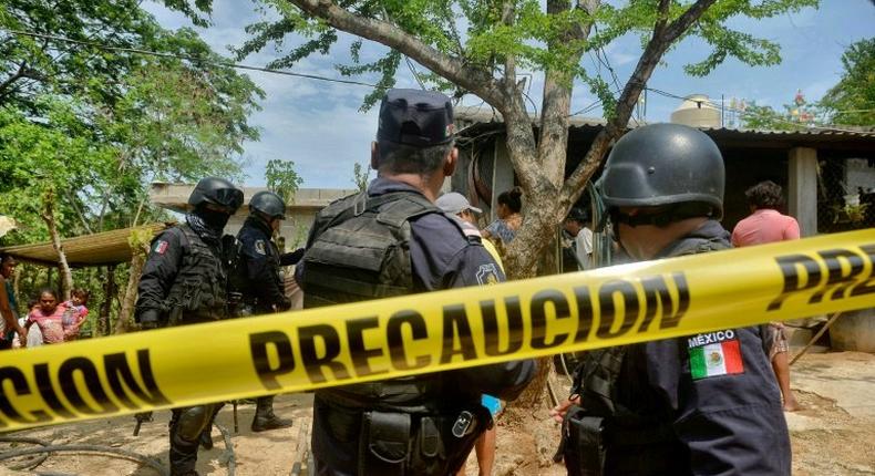 Police stand outside the house where were six people, including a four-month-old baby, were killed by gunmen in San Pedro Cacahuatepec, Acapulco municipality, Mexico's Guerrero state, on June 9, 2017