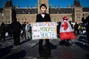 Osoba nosząca maskę Monopoly Man trzyma znak podczas wiecu przeciwko ograniczeniom COVID-19 na Parliament Hill w Ottawie, Kanada, w sobotę, 29 stycznia 2022 r.