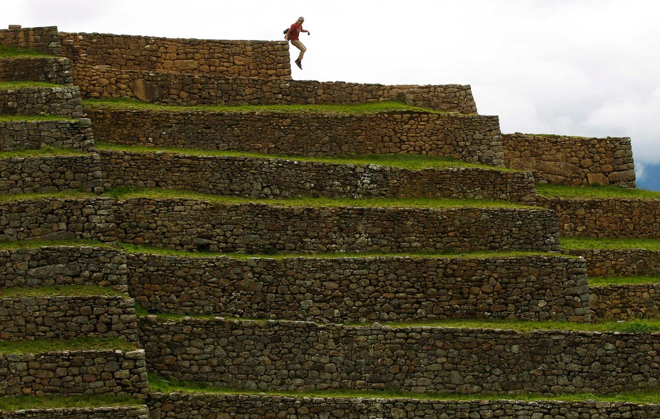 A tourist jumps from a terrace at the Inca citadel of Machu Picchu in Cuzco