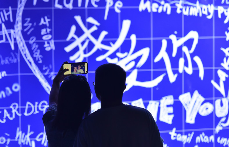 Para robi sobie selfie przed ścianą z napisem "kocham cię" w różnych językach podczas Festiwalu Qixi, czyli chińskich Walentynek