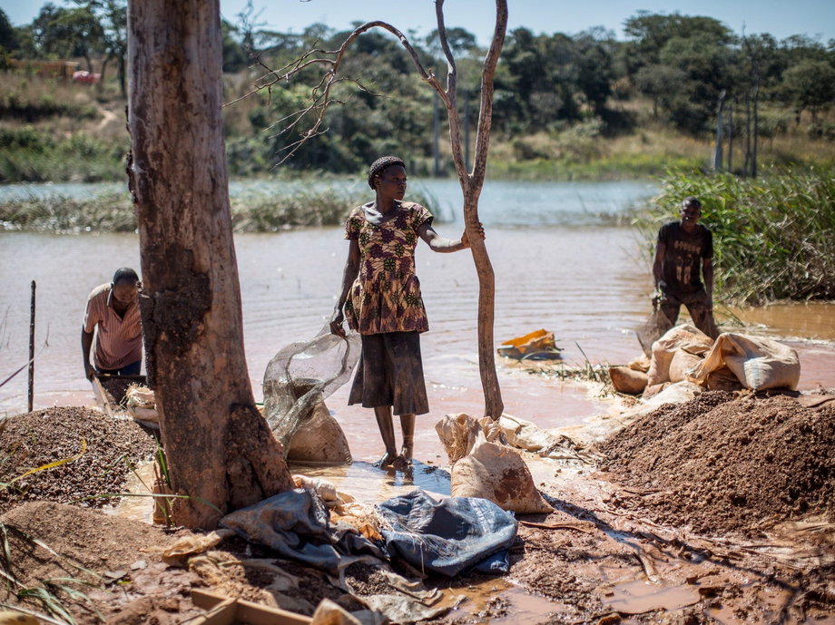 Kobieta i mężczyźni oddzielają kobalt od błota i skał w pobliżu kopalni pomiędzy Lubumbashi i Kolwezi. To kilkoro z 130 000 drobnych kopaczy próbujących wyżyć z bogatej ziemi regionu.  