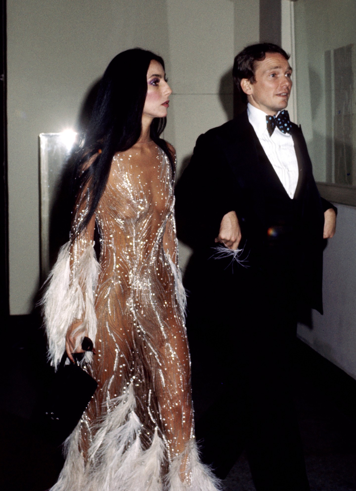 1974, Cher - Az 1974-es Met-gálán, amelynek témája a „Romantikus és elbűvölő hollywoodi dizájn” volt, a vörös szőnyeg egyik ikonikus megjelenését viselte. A gyöngyökkel és tollakkal díszített ruhát Bob Mackie tervezte. Ugyanebben az évben újra viselte a látványos darabot a Vogue és a Time címlapján is. És ez csak egy a sok pucérruha közül, amit az énekesnő az évek alatt viselt.