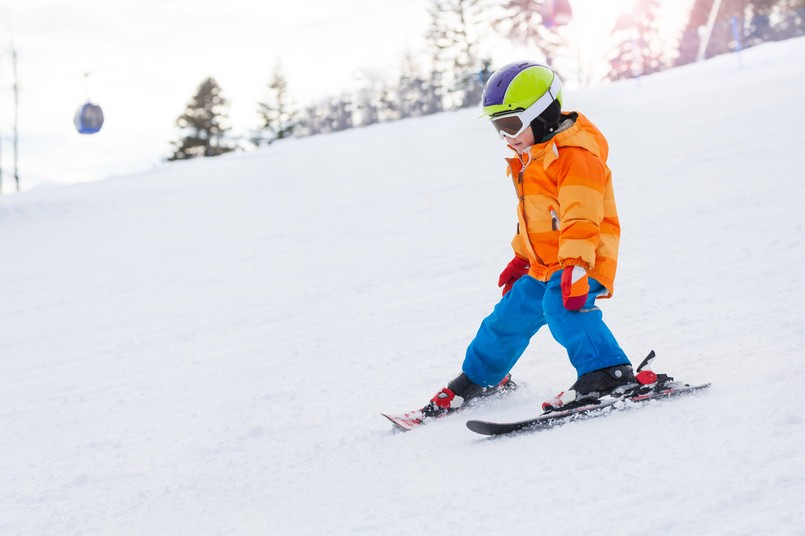 chłopiec uczy się jeździć na nartach