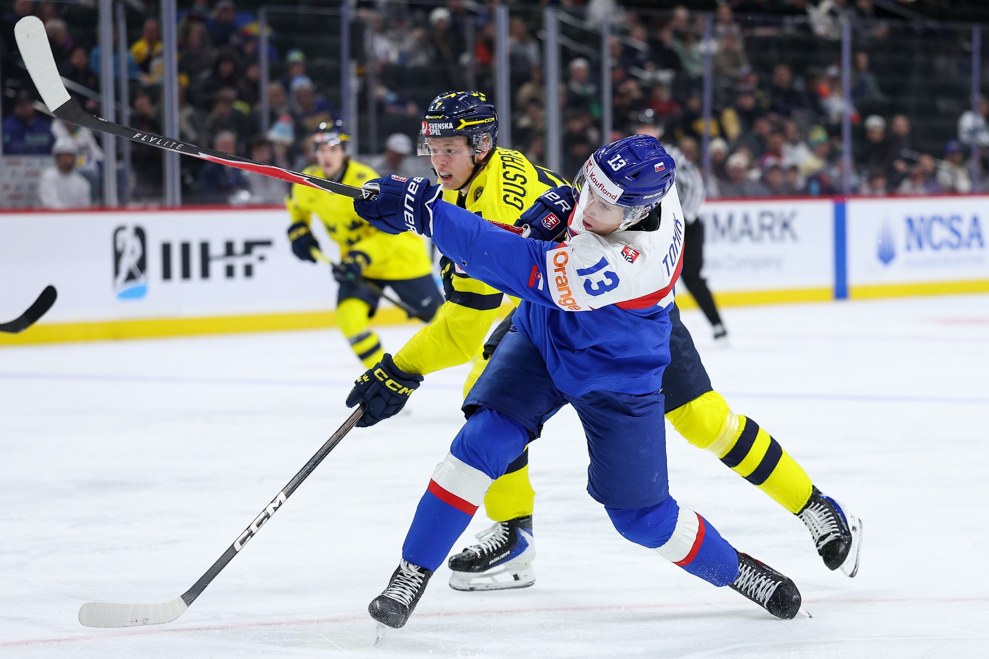 Slovenský hokejista Tobias Tomík (vpravo) strieľa na bránu, bráni ho hráč Švédska Viggo Gustafsson (uprostred). 
