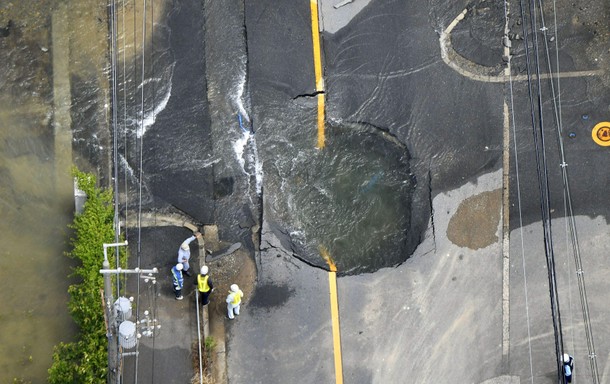 Water flows out from cracks in a road damaged by an earthquake in Takatsuki