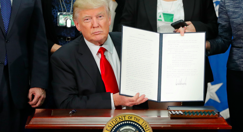 President Donald Trump holds up an executive order for border security and immigration enforcement improvements after signing the order during a visit to the Homeland Security Department headquarters in Washington, January 25, 2017.