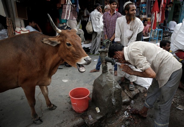 A man cools down at a water pump on a hot summers day in Old Delhi