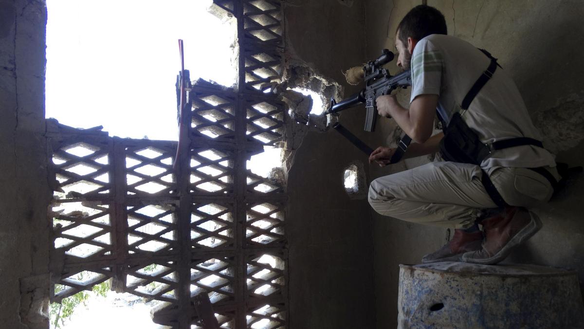 Bojownik Wolnej Armii Syryjskiej ostrzeliwuje pozycje sił wiernych Asadowi 