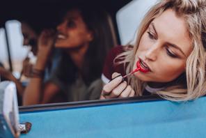 Ładna kobieta ze szminką przegląda się w samochodowym lusterku