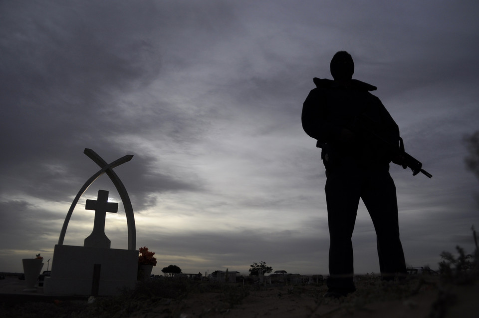 A police officer stands guard during the funeral of victims killed at a family birthday party, in Ciudad Juarez