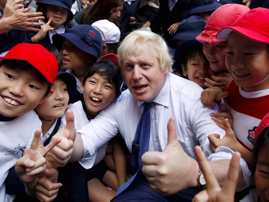 London's Mayor Boris Johnson poses for a photo with school children after a game of Street Rugby with a group of Tokyo children, outside the Tokyo Square Gardens building October 15, 2015.