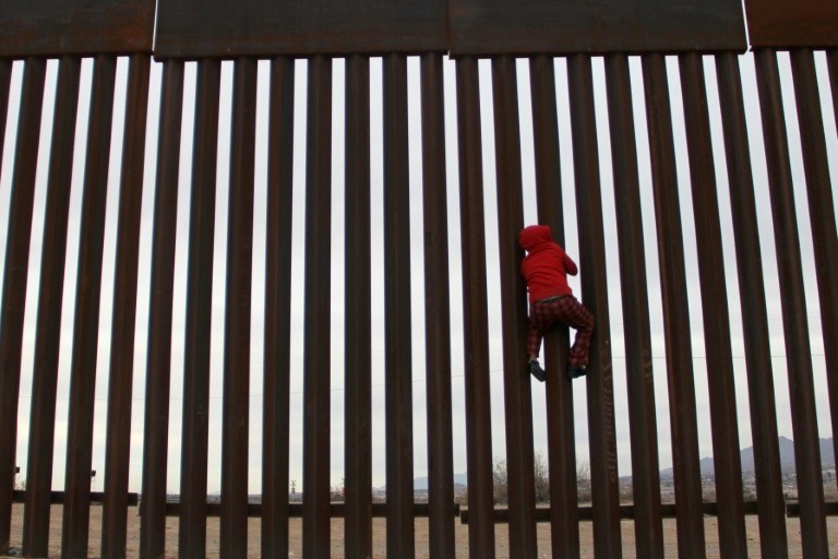 A boy in the poor Anapra neighborhood of Ciudad Juarez, Mexico, plays on the border fence across from Sunland Park, New Mexico, in the US side