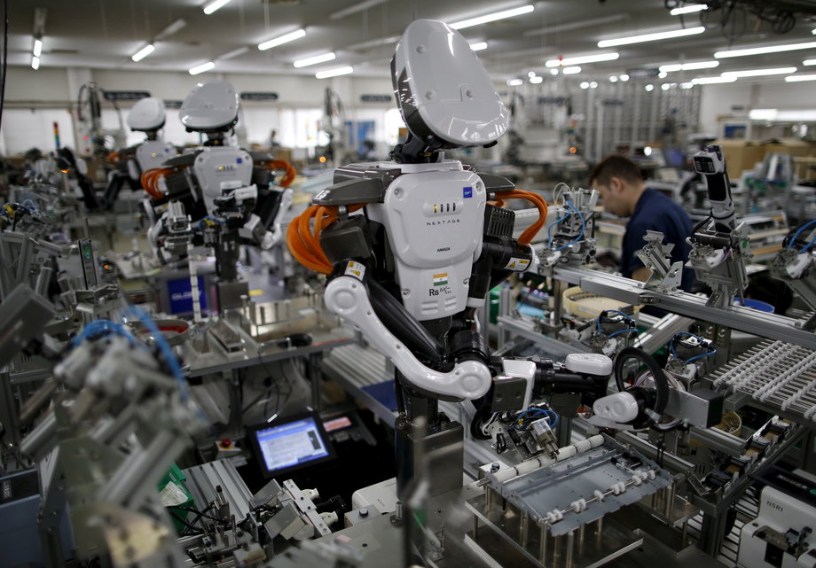 Humanoid robots work side by side with employees in the assembly line at a factory of Glory Ltd., a manufacturer of automatic change dispensers, in Kazo, north of Tokyo, Japan, July 1, 2015.