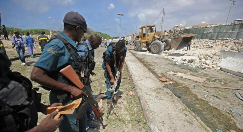 Somali soldiers secure a partially-crumbled perimeter wall following twin car bombings outside UN buildings in Mogadishu on July 26 
