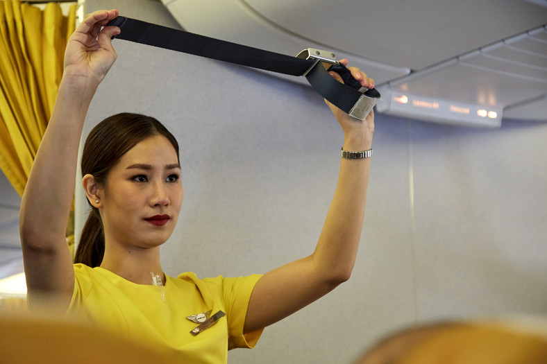 Stewardesa tłumacząca pasażerom zasady bezpieczeństwa podczas lotu