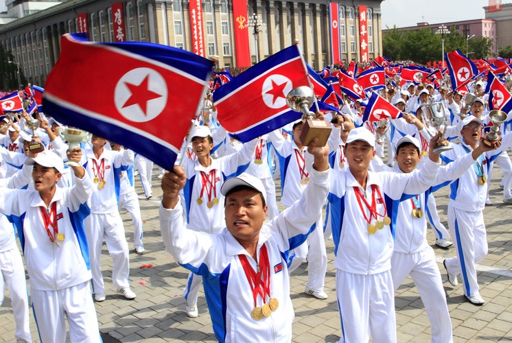 Stroje w barwach narodowych, w dłoniach północnokoreańskie flagi