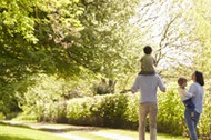 Rear View Of Family Going For Walk In Summer Countryside