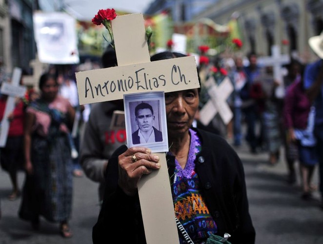 Kobieta z plemienia Maya w Narodowym Dniu Godności niesie krzyż ze zdjęciem swego męża zaginionego w czasie konfliktu w Gwatemali