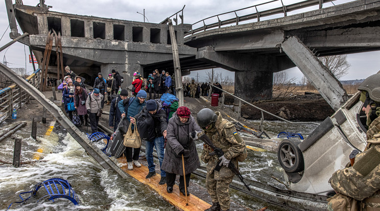 Katonák segítenek a Kijev közelében lévő Irpinyből menekülő embereknek átkelni egy orosz légicsapásban lerombolt híd alatt kialakított átkelőn az Irpiny folyón 2022. március 7-én / Fotó: MTI/EPA/Roman Pilipej
