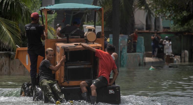 Workers move in a dump truck in a street flooded by sea water that breaks on the Malecon, in the aftermath of Hurricane Ian in Havana, Cuba, Thursday, Sept. 29, 2022.