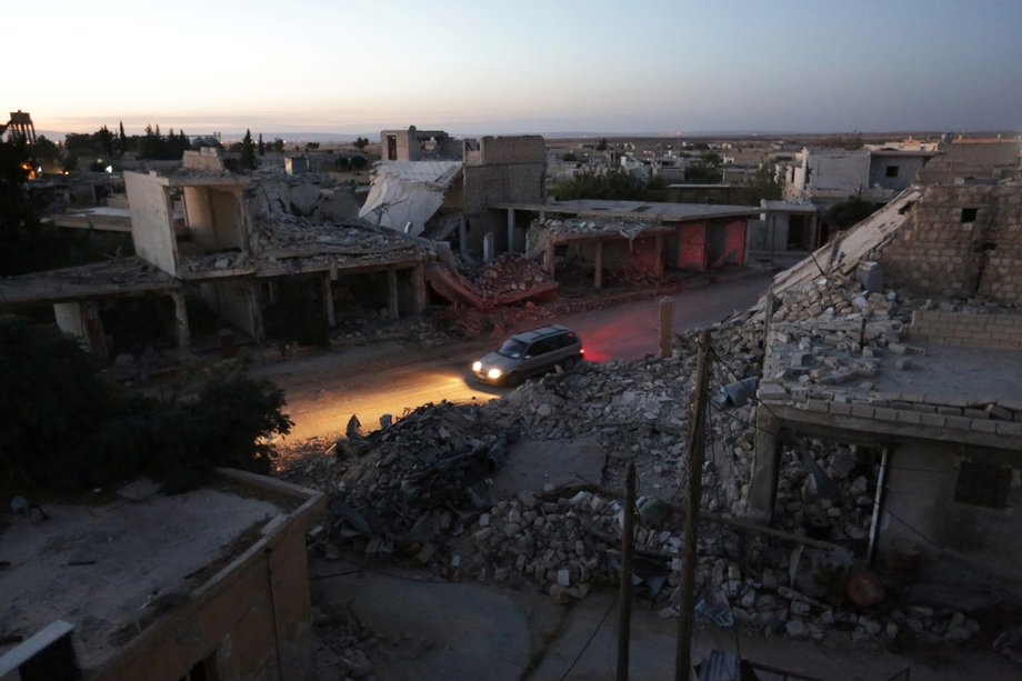 A vehicle drives past damaged buildings in the northern Syrian rebel-controlled town of al-Rai, in Aleppo Governorate, Syria, September 26, 2016.