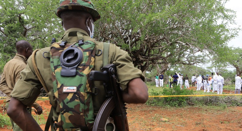 Kenya police officers stand guard as the bodies of suspected members of a Christian cult named as Good News International Church are exhumed in Shakahola forest in Kenya, April 22, 2023.Stringer/Reuters