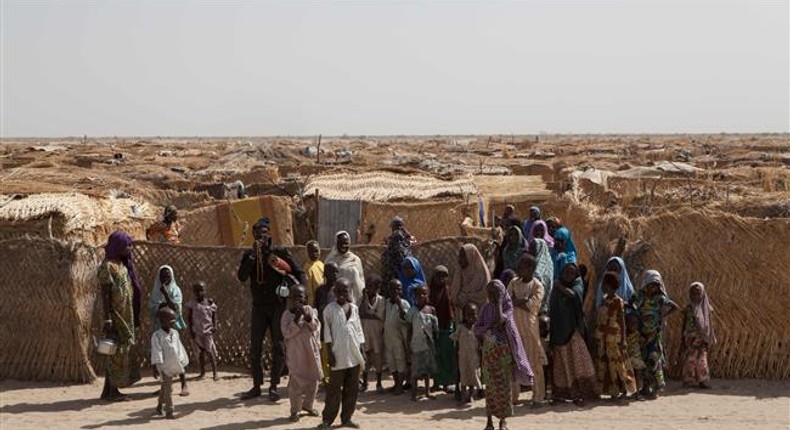 Displaced families stand at the main gate of a camp for internally displaced people at Monguno district of Borno State on February 14, 2017.