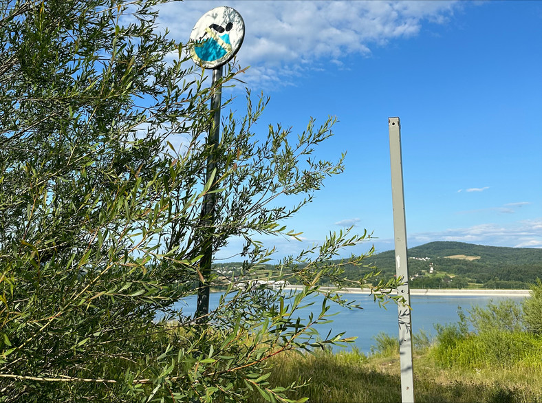 Wyblakły znak zakazujący kąpieli od strony dawnego kamieniołomu we wsi Skawce