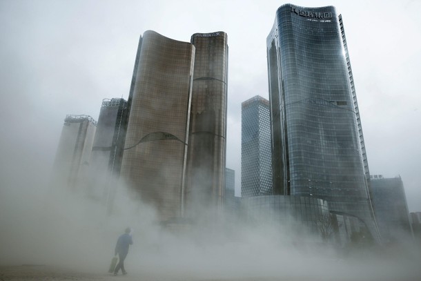 A man walks through a cloud of dust whipped up by wind at the construction site near newly erected o