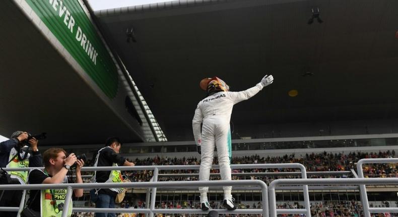 Mercedes' British driver Lewis Hamilton waves to fans after taking pole position in qualifying for the Formula One Chinese Grand Prix in Shanghai