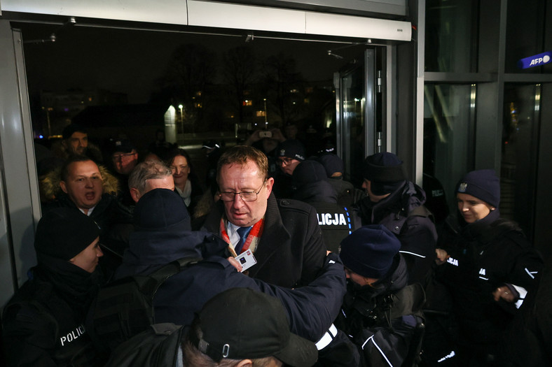 Posłowie PiS przedzierający się przez kordony policyjne w siedzibie TVP