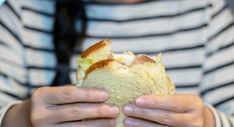 A child eats a sandwich.yipengge/Getty