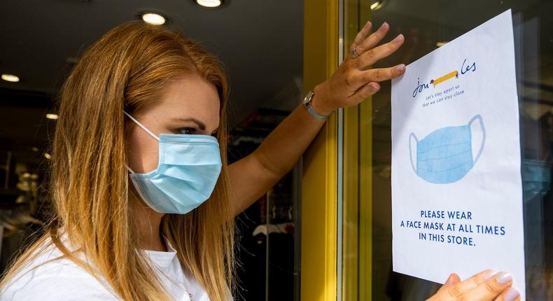 Joanne Millar store manger of Joules in Belfast places a sign in the shop window advising customers that face masks must be worn at all times as face coverings are now compulsory for shoppers.
