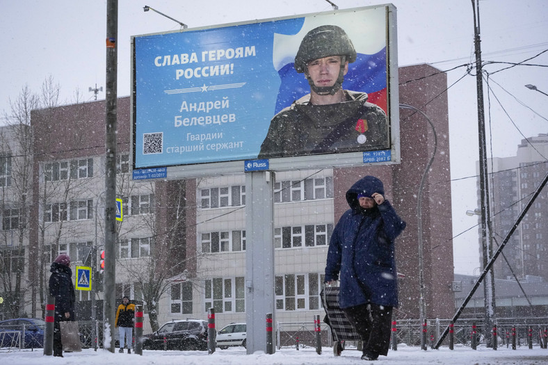 Kobieta przechodzi obok billboardu z portretem rosyjskiego żołnierza nagrodzonego za walkę w Ukrainie i napisem "Chwała bohaterom Rosji" w Petersburgu, Rosja, wtorek, 3 stycznia 2023 r.