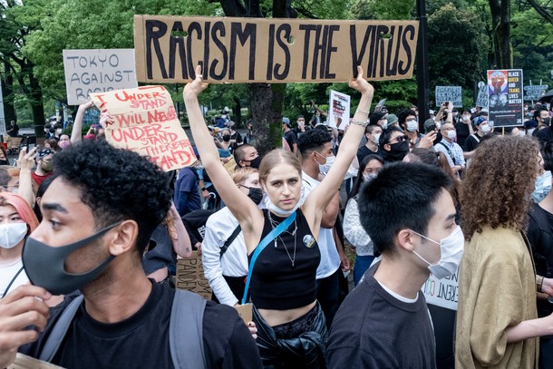 Protesty BLM w Japonii. Kobieta trzyma karton z napisem „Rasizm to wirus podczas demonstracji w Tokio. 