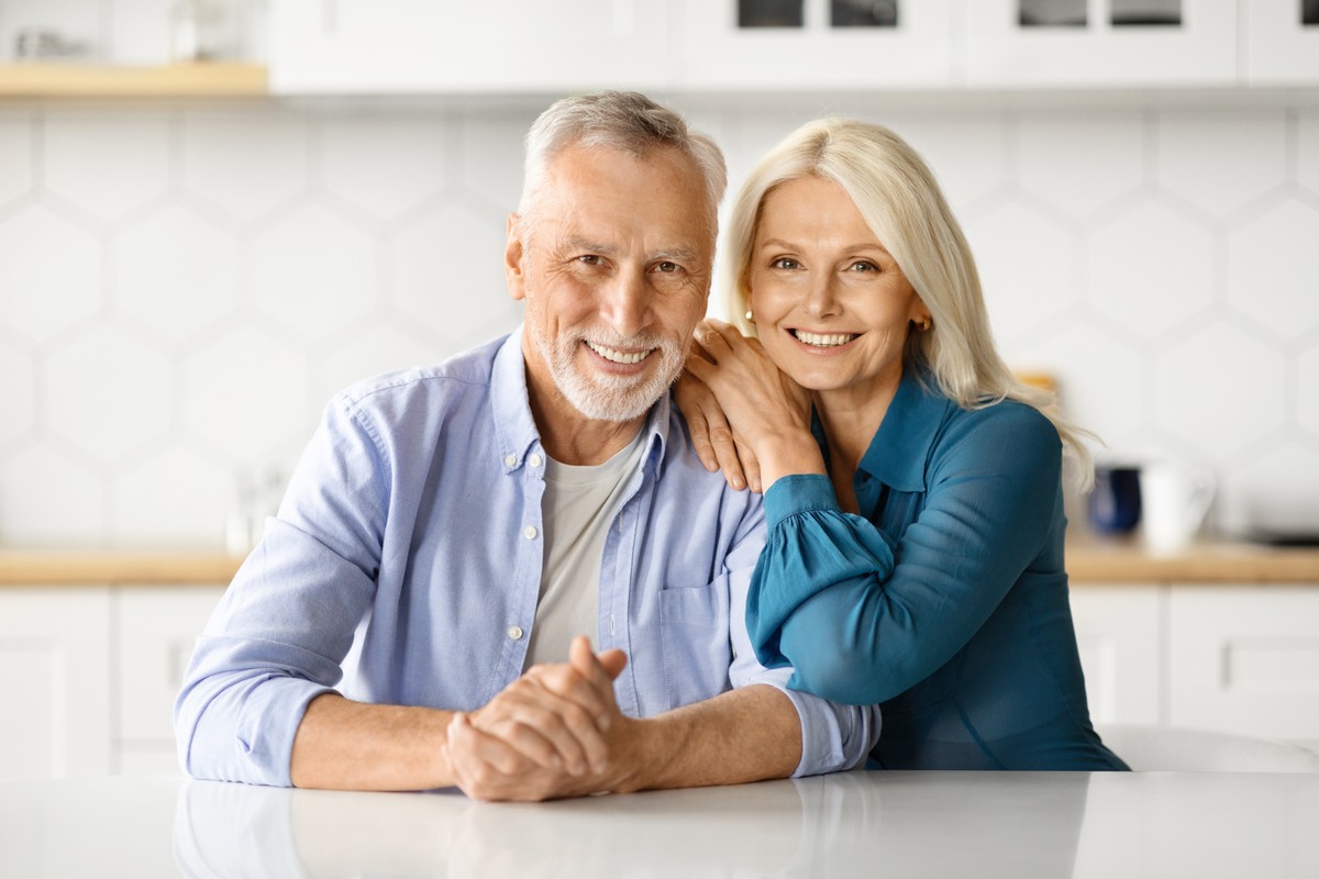 Zadowoleni emeryci uśmiechają się i siedzą przy stole w kuchni