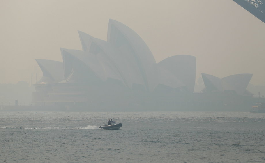 Sydney Opera House - symbol Australii i najsłynniejszy obiekt w mieście otoczony dymem unoszącym się z płonącego buszu, listopad 2019 r. 