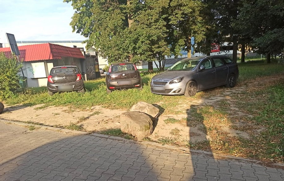 Odsunięte kamienie i kierowcy parkujący na trawniku w parku