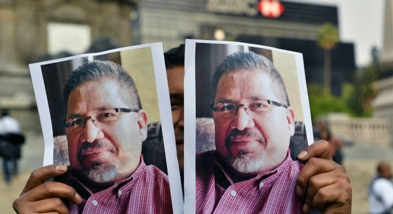 A photojournalist shows pictures of Mexican journalist Javier Valdez, murdered a day earlier, during a protest in Mexico City on May 16, 2017