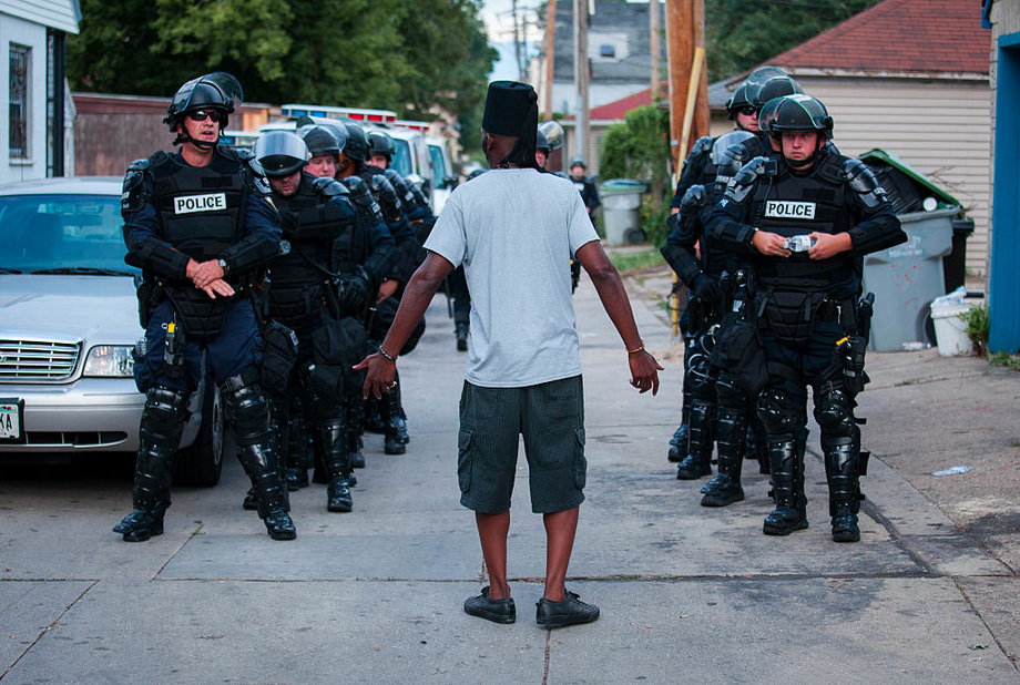 A man talks to police in riot gear as they wait in an alley after a second night of clashes between protestors and police August 15, 2016 in Milwaukee, Wisconsin.