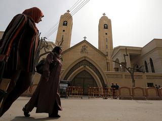 Women pass by the Coptic church that was bombed on Sunday in Tanta