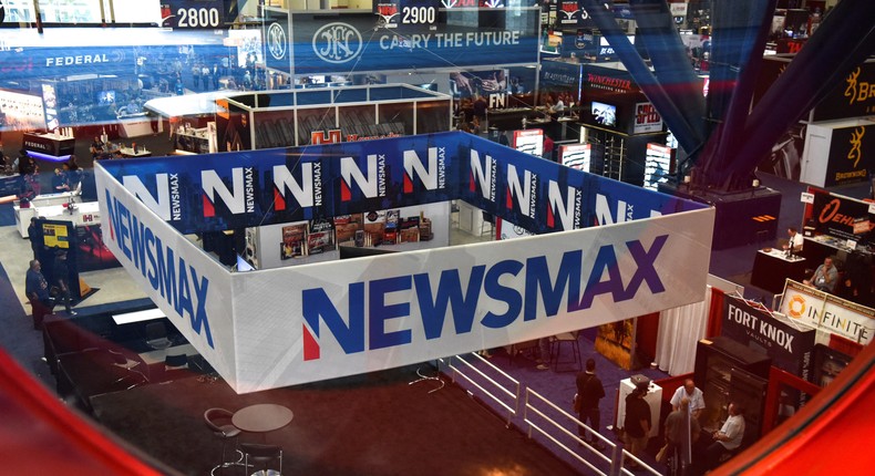 A Newsmax booth broadcasts as attendees try out the guns on display at the National Rifle Association (NRA) annual convention in Houston, Texas, on May 29, 2022.