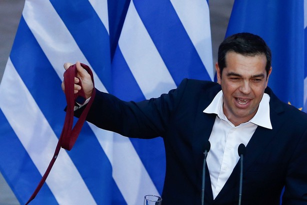 Greek Prime Minister Alexis Tsipras, holds his tie, as he speaks at the parliamentary group of Syriz