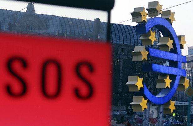 Rzeźba z logo Europejskiego Banku Centralnego ze znakiem SOS w pobliskiej budce telefonicznej we Frankfurcie nad Menem.